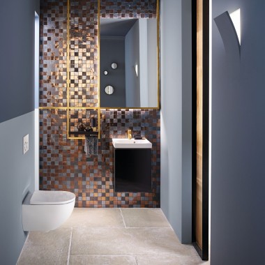 Vista su un moderno WC degli ospiti con un WC e un lavabo Acanto davanti a una parete posteriore in mosaico.