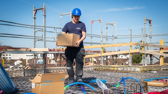 Ein Mann testet die neue Geberit Einlegerohrschelle auf der Baustelle Ein Mann testet die neue Geberit Einlegerohrschelle auf der Baustelle