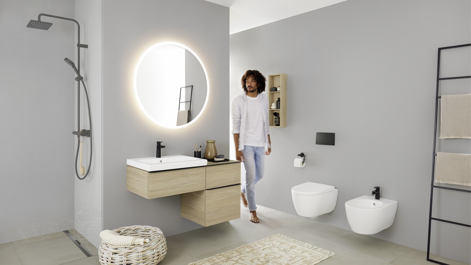 Homme entrant dans une salle de bains équipée d’un lavabo, d’un WC, d’un bidet et de meubles de la série Geberit iCon. Homme entrant dans une salle de bains équipée d’un lavabo, d’un WC, d’un bidet et de meubles de la série Geberit iCon.