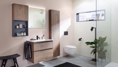 Un espace lavabo avec des meubles de salle de bains, un lavabo et une armoire de toilette de Geberit devant une paroi aux couleurs pastel