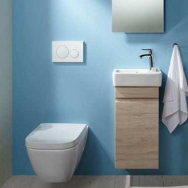 Un WC suspendu Renova Plan et un espace lavabo sont fixés sur un mur bleu clair