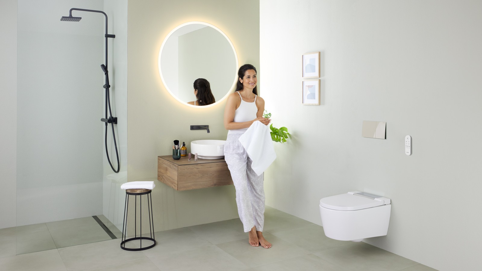 Donna appoggiata sul lavabo in un bagno con WCdoccetta Geberit AquaClean Sela Donna appoggiata sul lavabo in un bagno con WCdoccetta Geberit AquaClean Sela