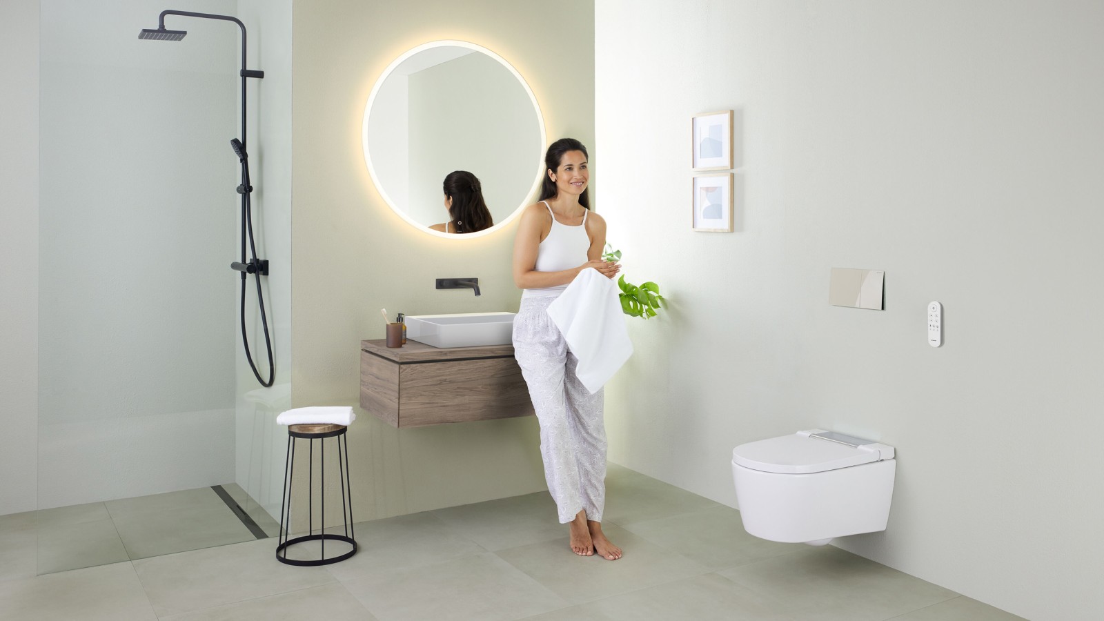 Femme appuyée sur un lavabo dans une salle de bains avec un WCdouche Geberit AquaClean Sela Femme appuyée sur un lavabo dans une salle de bains avec un WCdouche Geberit AquaClean Sela