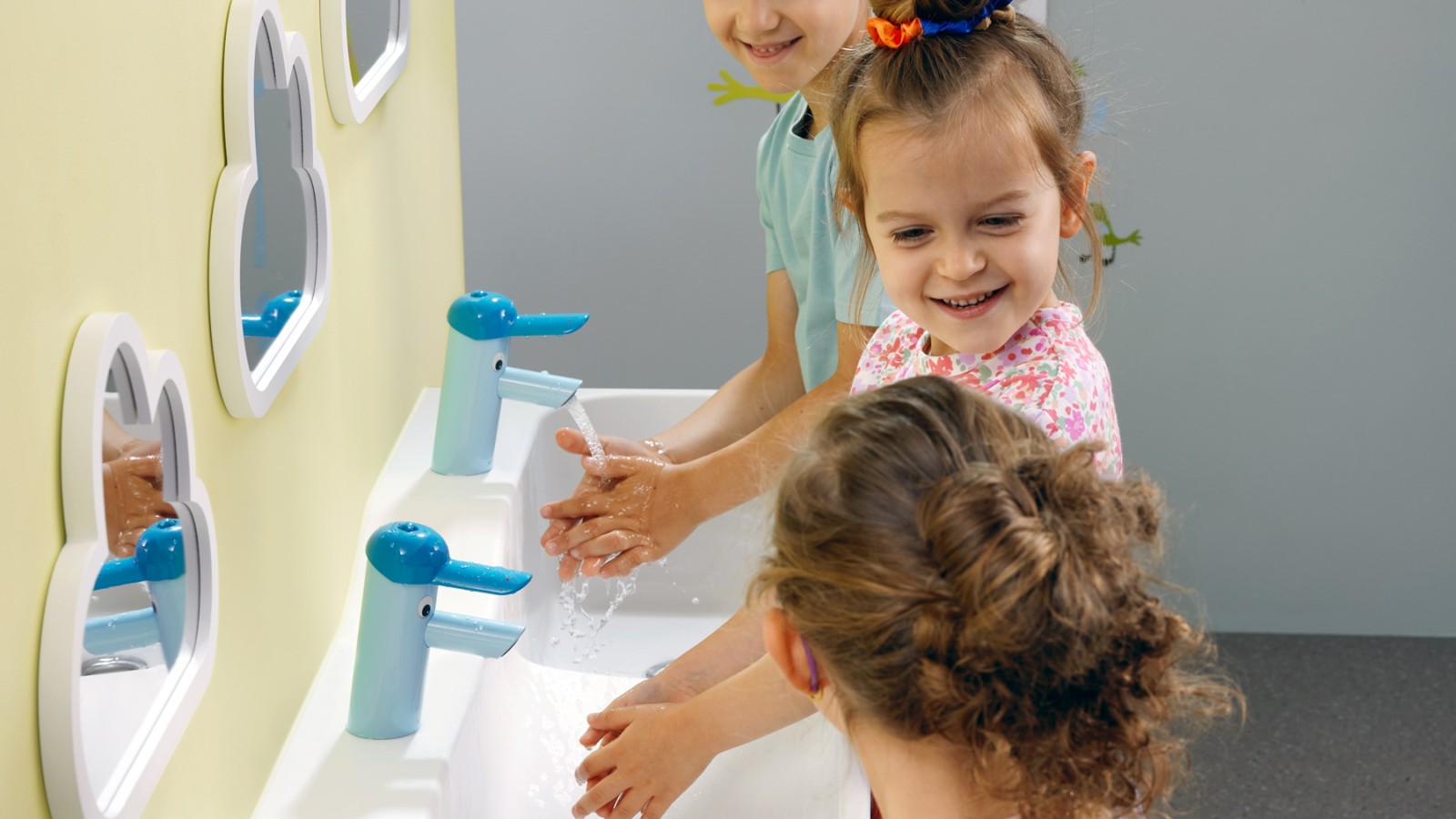 Kinder spielen an einer Geberit Bambini Spiel- und Waschlandschaft