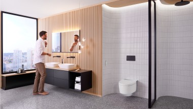 Homme dans la salle de bains devant le miroir Geberit Option Plus Square et les meubles de salle de bains noirs Geberit ONE (© Geberit)
