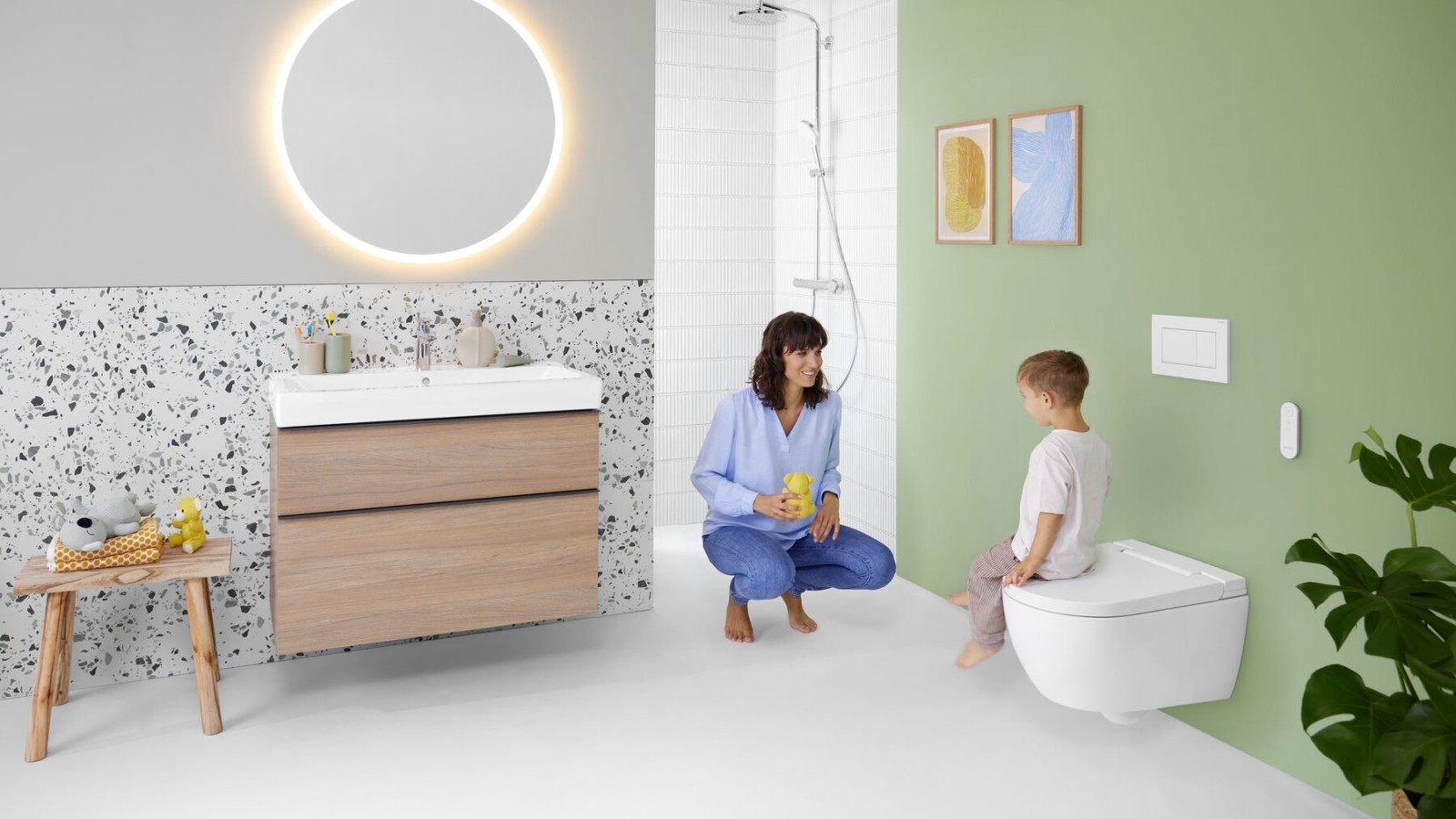 Femme et enfant dans une salle de bains colorée dotée d’un miroir Geberit Option et d’un Geberit AquaClean Alba Femme et enfant dans une salle de bains colorée dotée d’un miroir Geberit Option et d’un Geberit AquaClean Alba