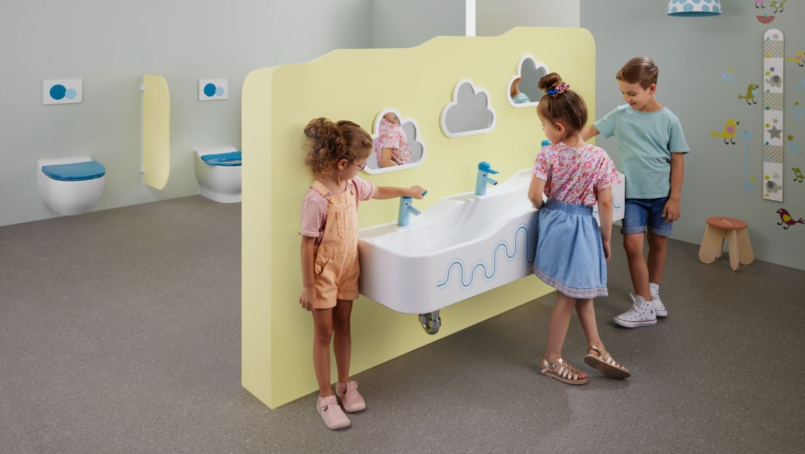 Kinder spielen in einem mit Geberit Bambini ausgestatteten Sanitärraum Kinder spielen in einem mit Geberit Bambini ausgestatteten Sanitärraum