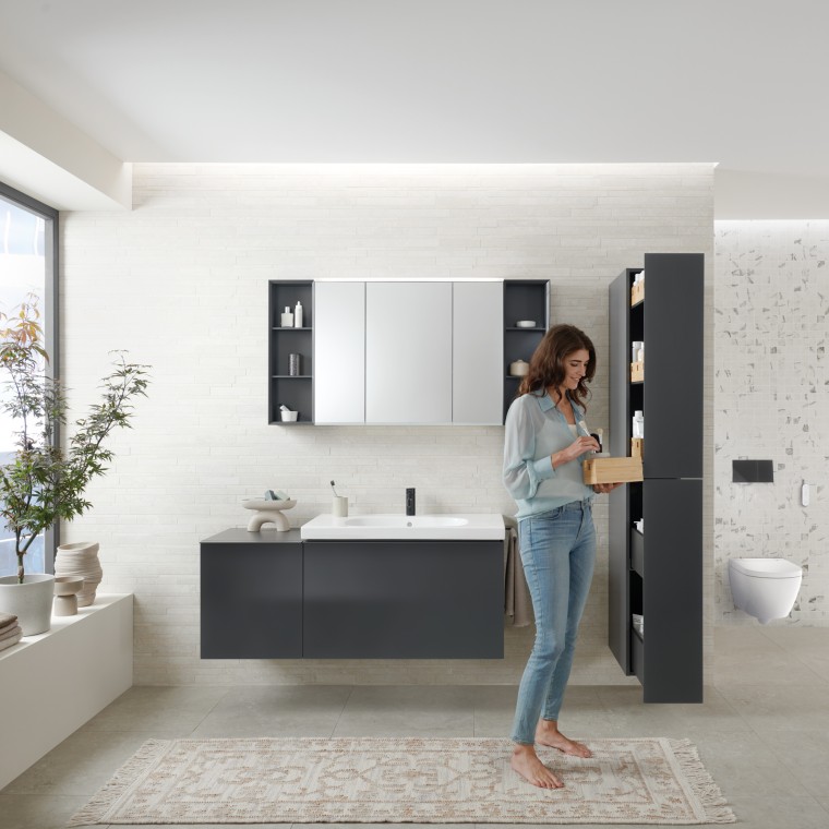 Femme ouvrant une armoire haute avec de généreux espaces de rangement de la série Geberit Acanto Femme ouvrant une armoire haute avec de généreux espaces de rangement de la série Geberit Acanto