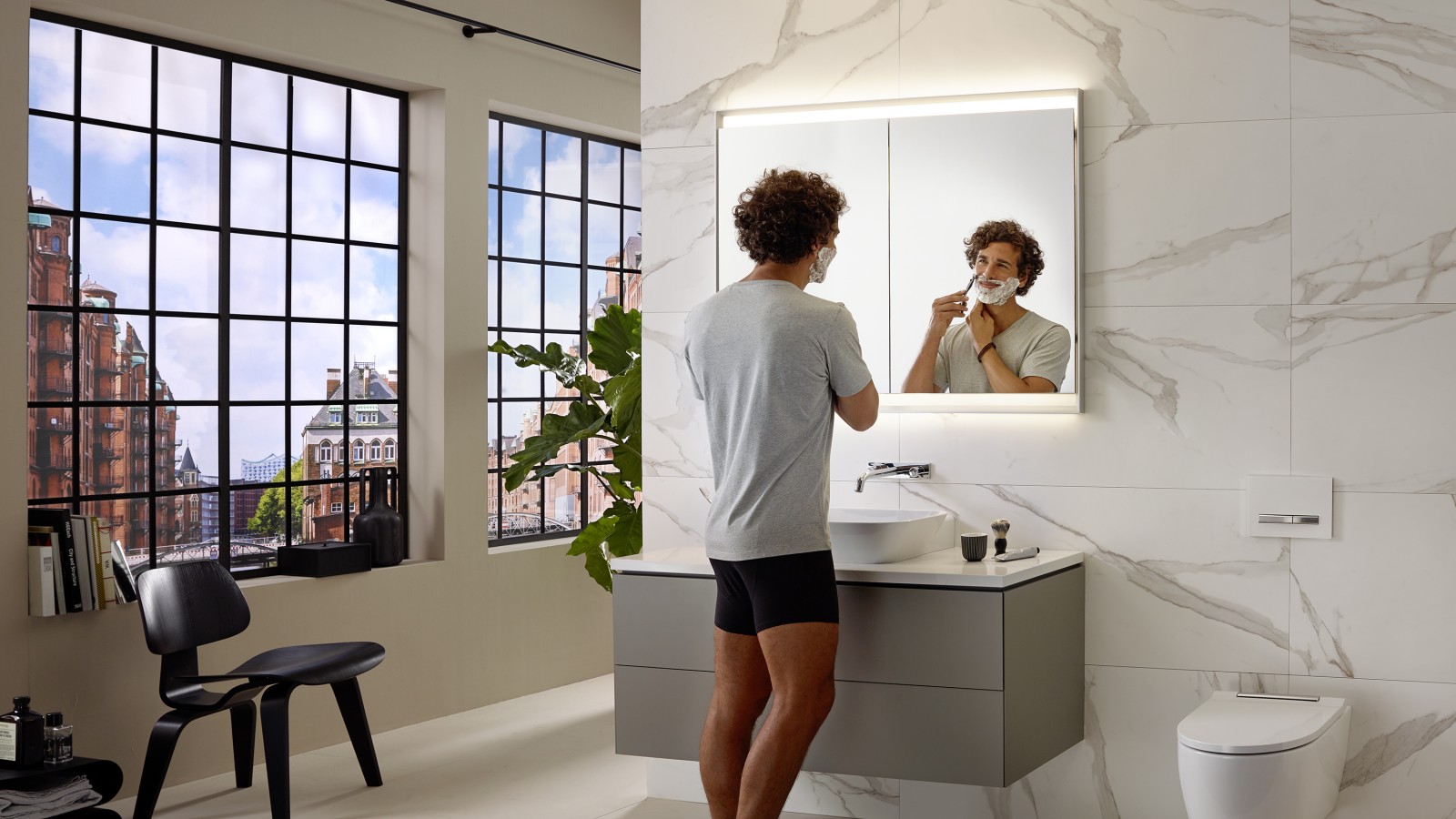 Uomo che si fa la barba al lavabo con mobile e specchio Geberit ONE Uomo che si fa la barba al lavabo con mobile e specchio Geberit ONE