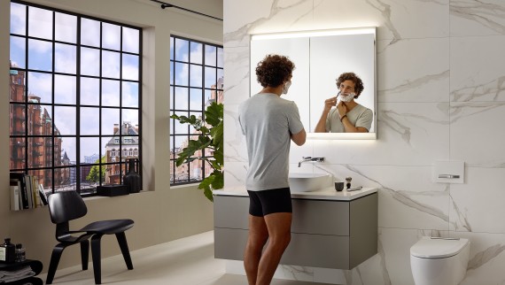 Uomo che si fa la barba al lavabo con mobile e specchio Geberit ONE