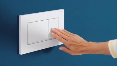 Hand löst auf der weissen Sigma20 Betätigungsplatte eine Spülung aus (© Geberit)