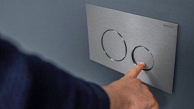 Hand löst kleine Spülung an der Sigma40 Round Betätigungsplatte aus (© Geberit)
