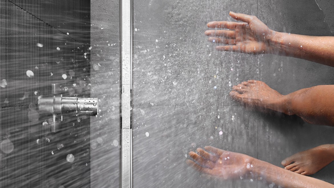 Persona in una doccia a filo del pavimento con canale per scarico doccia Geberit CleanLine