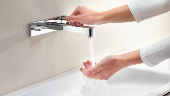 Macro immagine con le mani che girano un rubinetto Geberit ONE e controllano il flusso e la temperatura dell’acqua