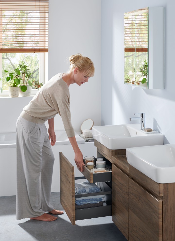 Une femme dans une salle de bains blanche de la série Geberit Renova Plan