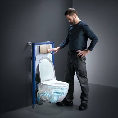 Un homme actionne le rinçage TurboFlush d'un WC Geberit Acanto Un homme actionne le rinçage TurboFlush d'un WC Geberit Acanto