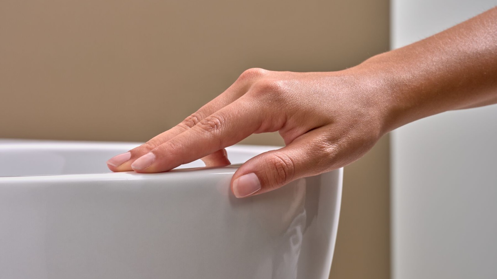 Una mano accarezza la ceramica del WC con vetrinatura speciale KeraTect® Una mano accarezza la ceramica del WC con vetrinatura speciale KeraTect®