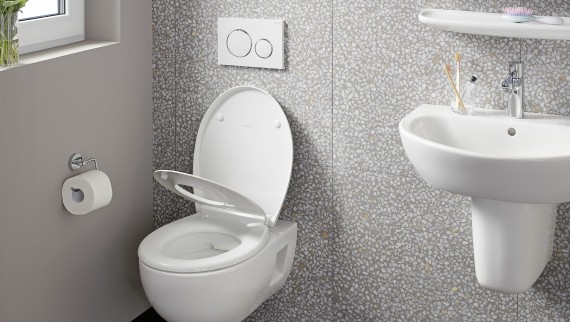 Wandhängendes WC an einer Wand mit Terrazzo-Fliesen Wandhängendes WC an einer Wand mit Terrazzo-Fliesen