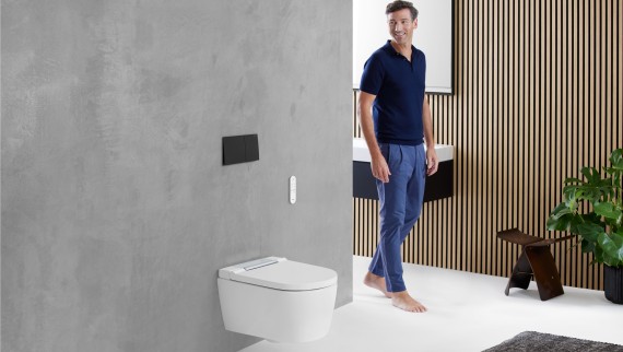 Uomo in bagno che guarda l'area WC, in cui si trova un WC di Geberit Uomo in bagno che guarda l'area WC, in cui si trova un WC di Geberit
