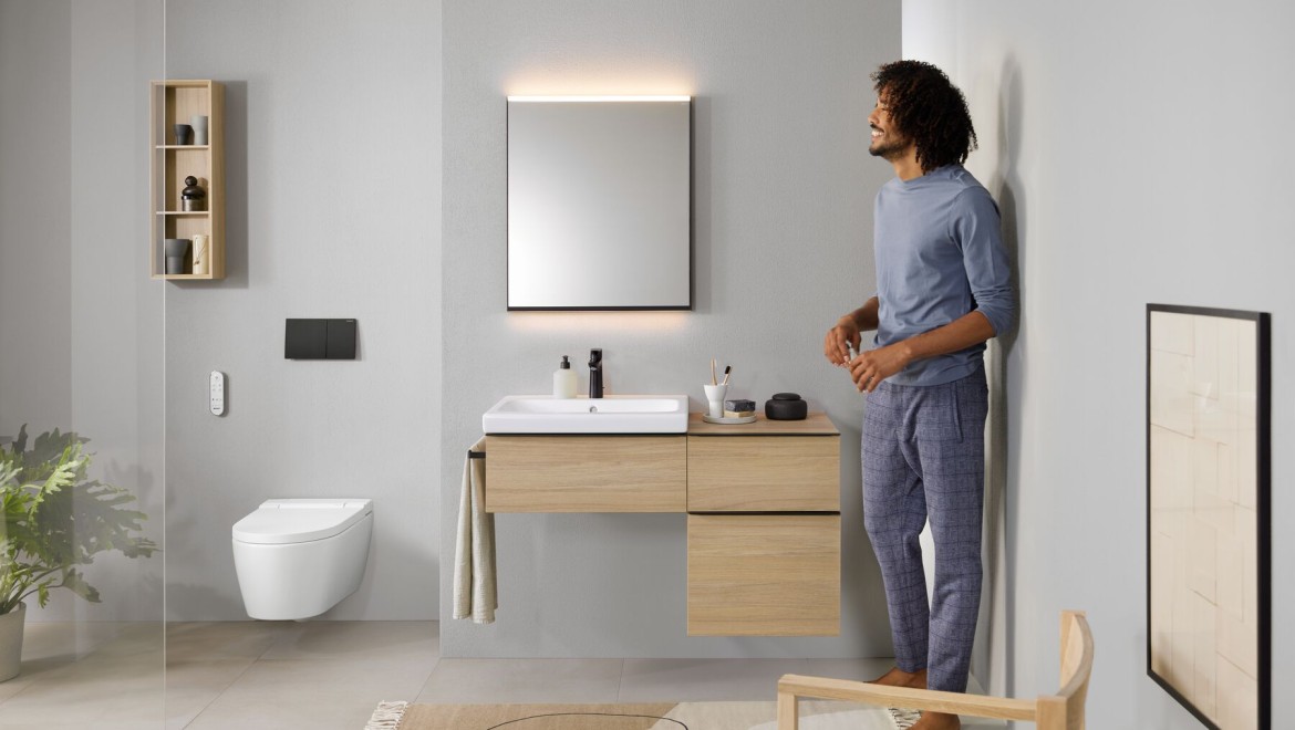 Mann steht in Bad mit Dusch-WC AquaClean Sela Mann steht in Bad mit Dusch-WC AquaClean Sela