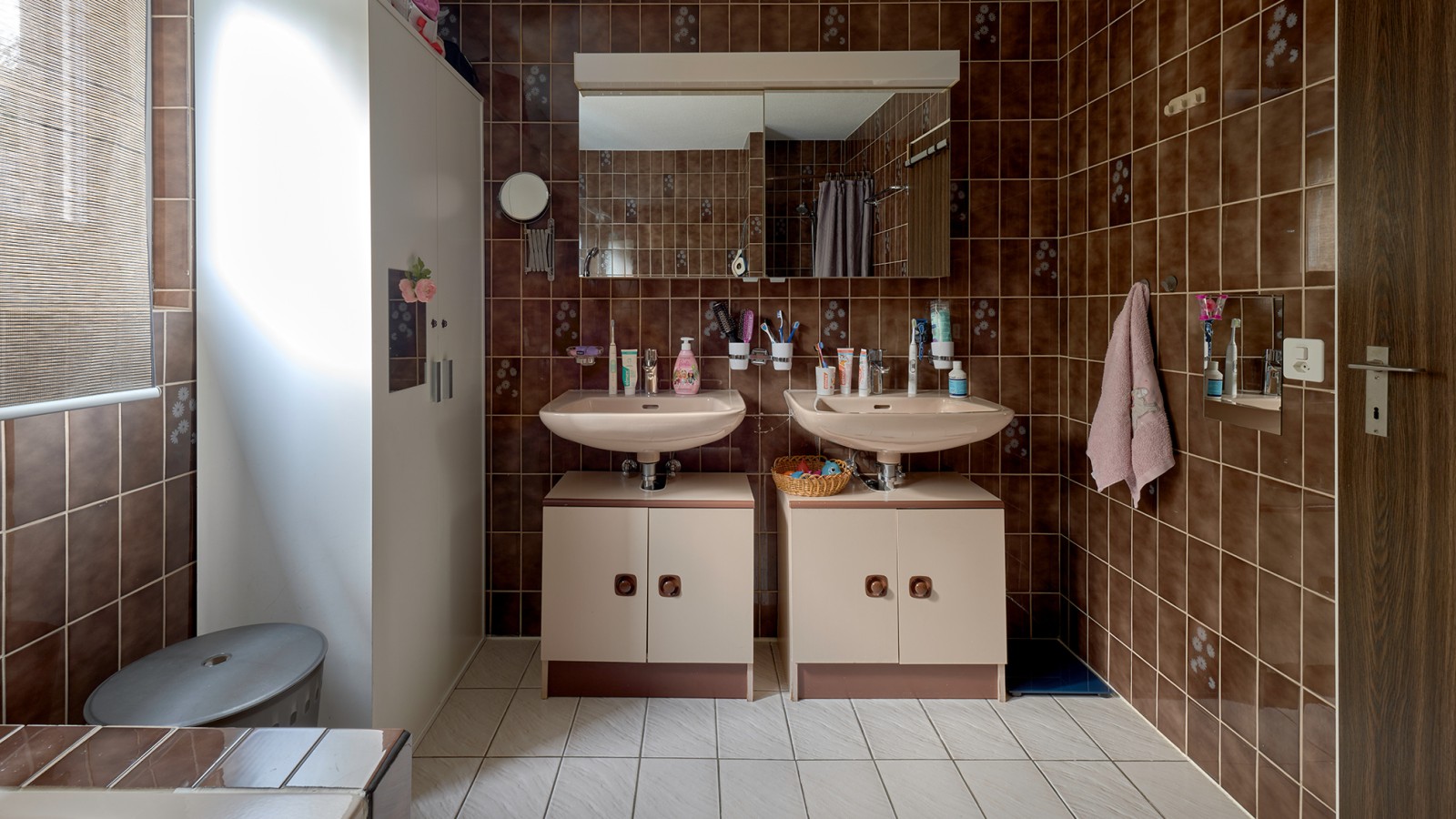 Salle de bains dotée d’un carrelage marron et de deux lavabos Salle de bains dotée d’un carrelage marron et de deux lavabos