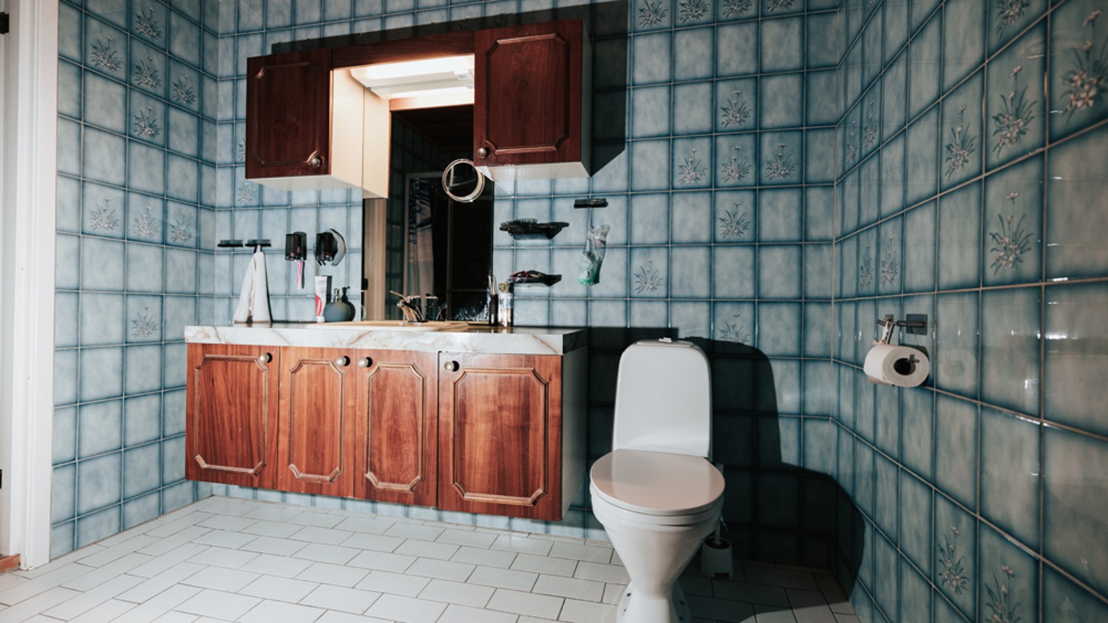 Salle de bains dotée d’un carrelage bleu et d’un WC au sol Salle de bains dotée d’un carrelage bleu et d’un WC au sol