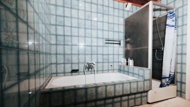 Bagno con piastrelle blu, cabina doccia e vasca da bagno
