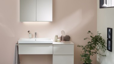 Una zona lavabo con mobili da bagno, lavabo e armadietto a specchio Geberit davanti a una parete color pastello