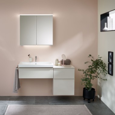 Ein Waschplatz mit Badmöbeln, Waschtisch und Spiegelschrank von Geberit vor einer pastellfarbenen Wand