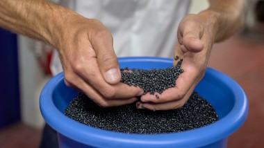 Mains tenant des granulés de plastique noir (© Ben Huggler)