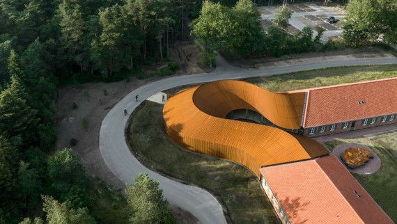 La vista dall’alto mostra il nuovo edificio rotondo che collega i due edifici storici con i tetti in tegole. (R_Hjortshoj)