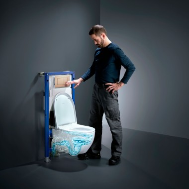 Homme à côté de WC Geberit Acanto avec TurboFlush, nouveau Geberit Duofix et plaque de déclenchement Sigma40 en or rose Homme à côté de WC Geberit Acanto avec TurboFlush, nouveau Geberit Duofix et plaque de déclenchement Sigma40 en or rose