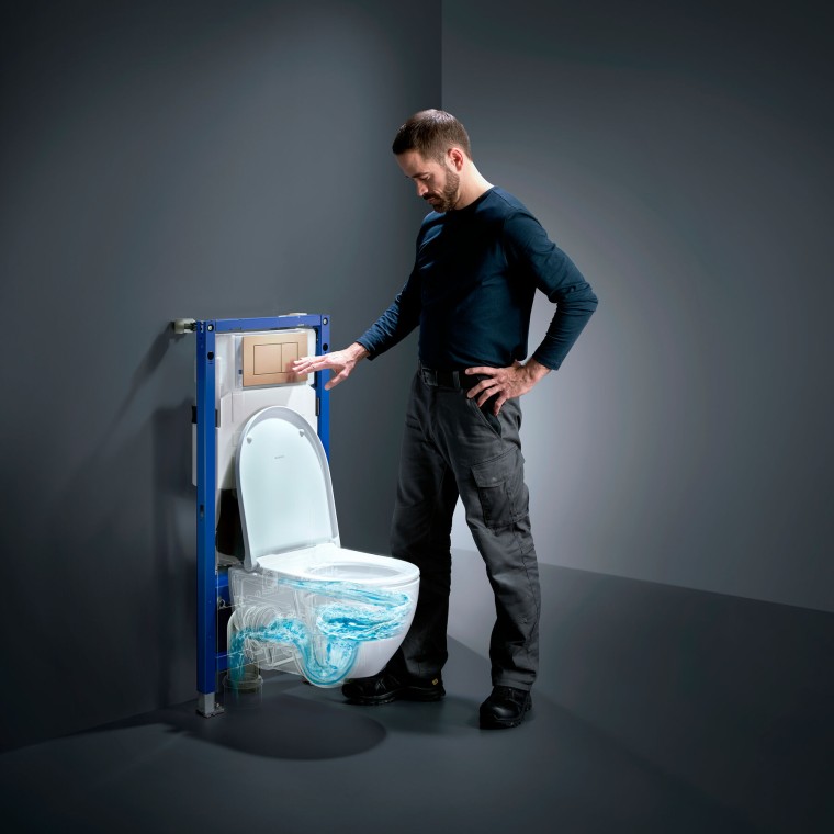Uomo accanto al WC Geberit Acanto con TurboFlush, al nuovo Geberit Duofix e alla placca di comando Sigma40 in oro rosso Uomo accanto al WC Geberit Acanto con TurboFlush, al nuovo Geberit Duofix e alla placca di comando Sigma40 in oro rosso