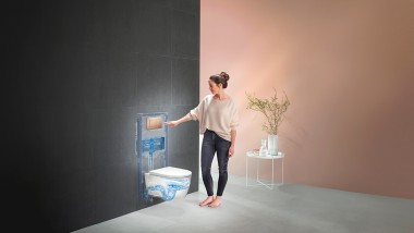 Frau löst Spülung beim Geberit WC-System aus (© Geberit)