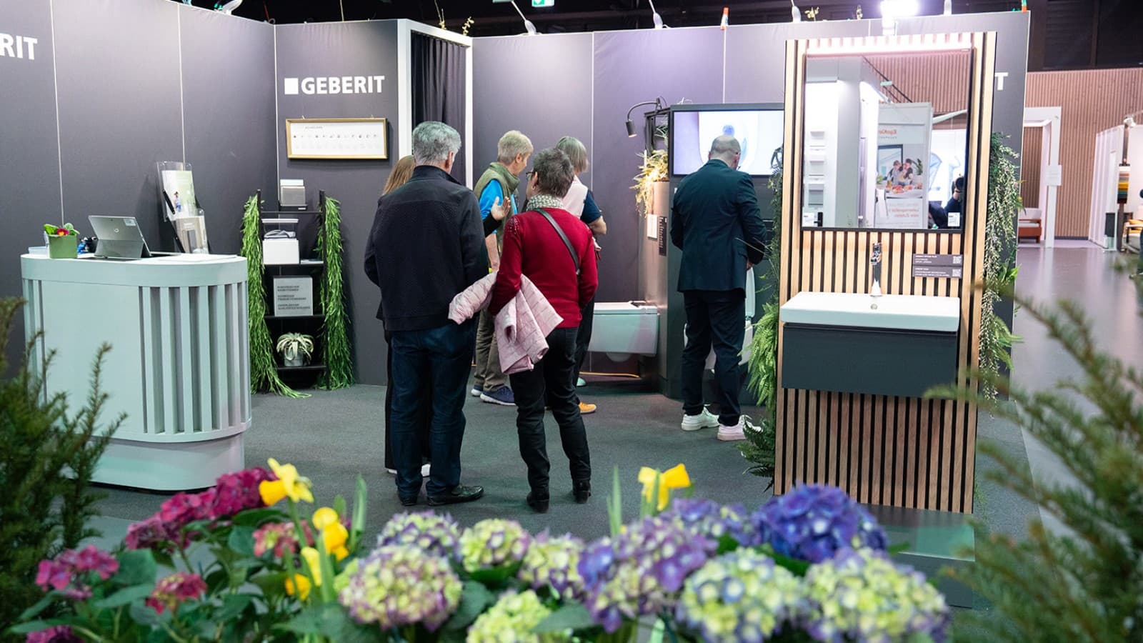 Geberit Messestand mit Besuchenden und ausgestellten Badlösungen Geberit Messestand mit Besuchenden und ausgestellten Badlösungen