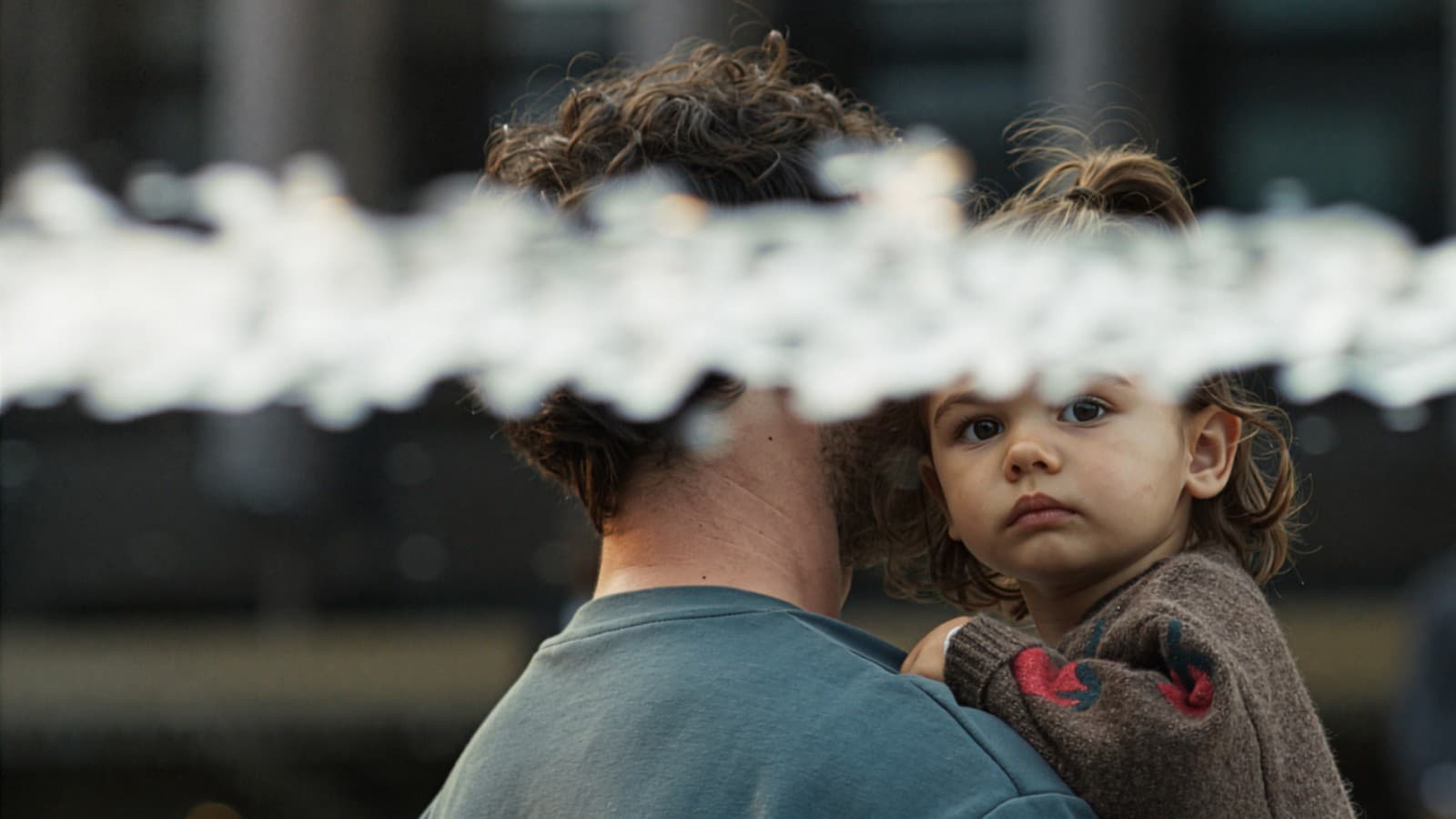 Une fille dans les bras de son père, avec un jet d'eau au premier plan Une fille dans les bras de son père, avec un jet d'eau au premier plan