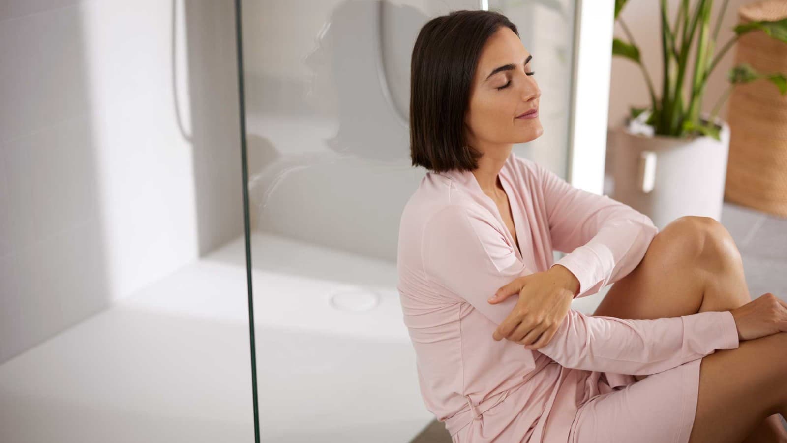 Femme assise devant la douche dans la salle de bains Femme assise devant la douche dans la salle de bains